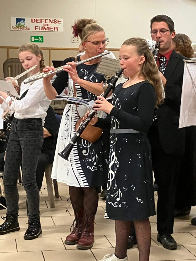 Musiciennes et musicien de l’Ensemble Instrumental Waremmien jouant flûte et clarinette en tenue noire et blanche lors du Concert Bestial à Tilleur