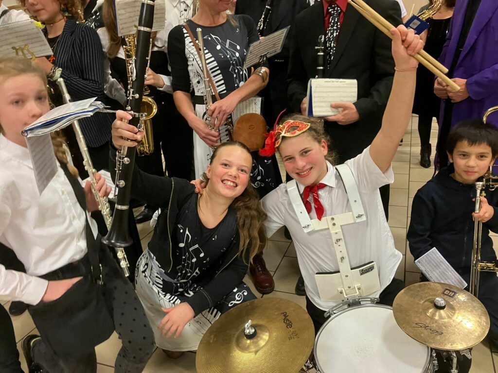 Jeunes musiciens souriants de l’Ensemble Instrumental Waremmien célébrant la fin du Concert Bestial à Tilleur