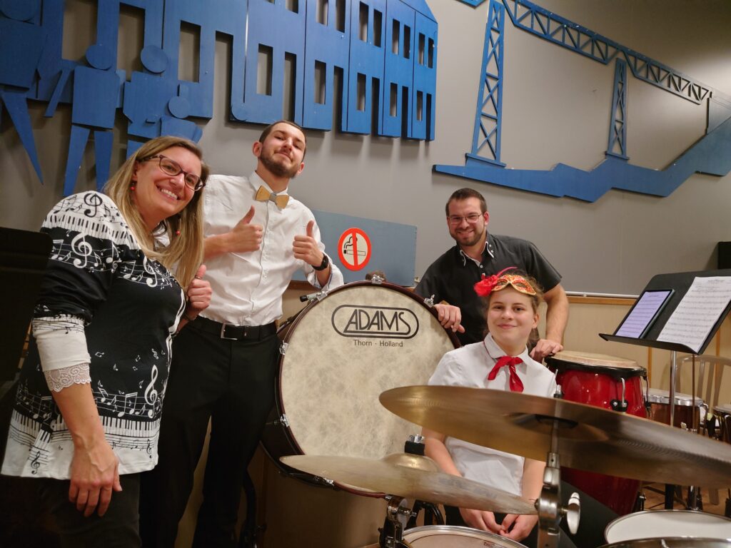 Équipe des percussions de l’Ensemble Instrumental Waremmien lors du Concert Bestial au centre culturel de Tilleur, avec jeunes et adultes en tenue blanche et noire
