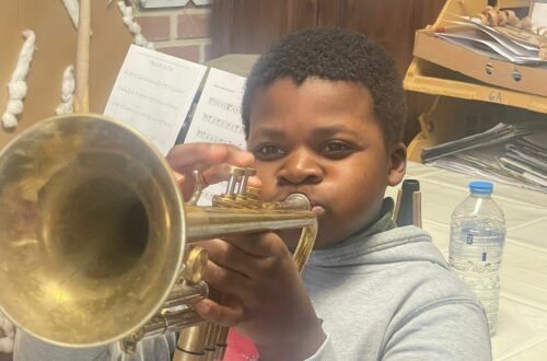 Un élève de 6ᵉ primaire essaye une trompette lors d’un atelier de découverte musicale avec l’Ensemble Instrumental Waremmien.